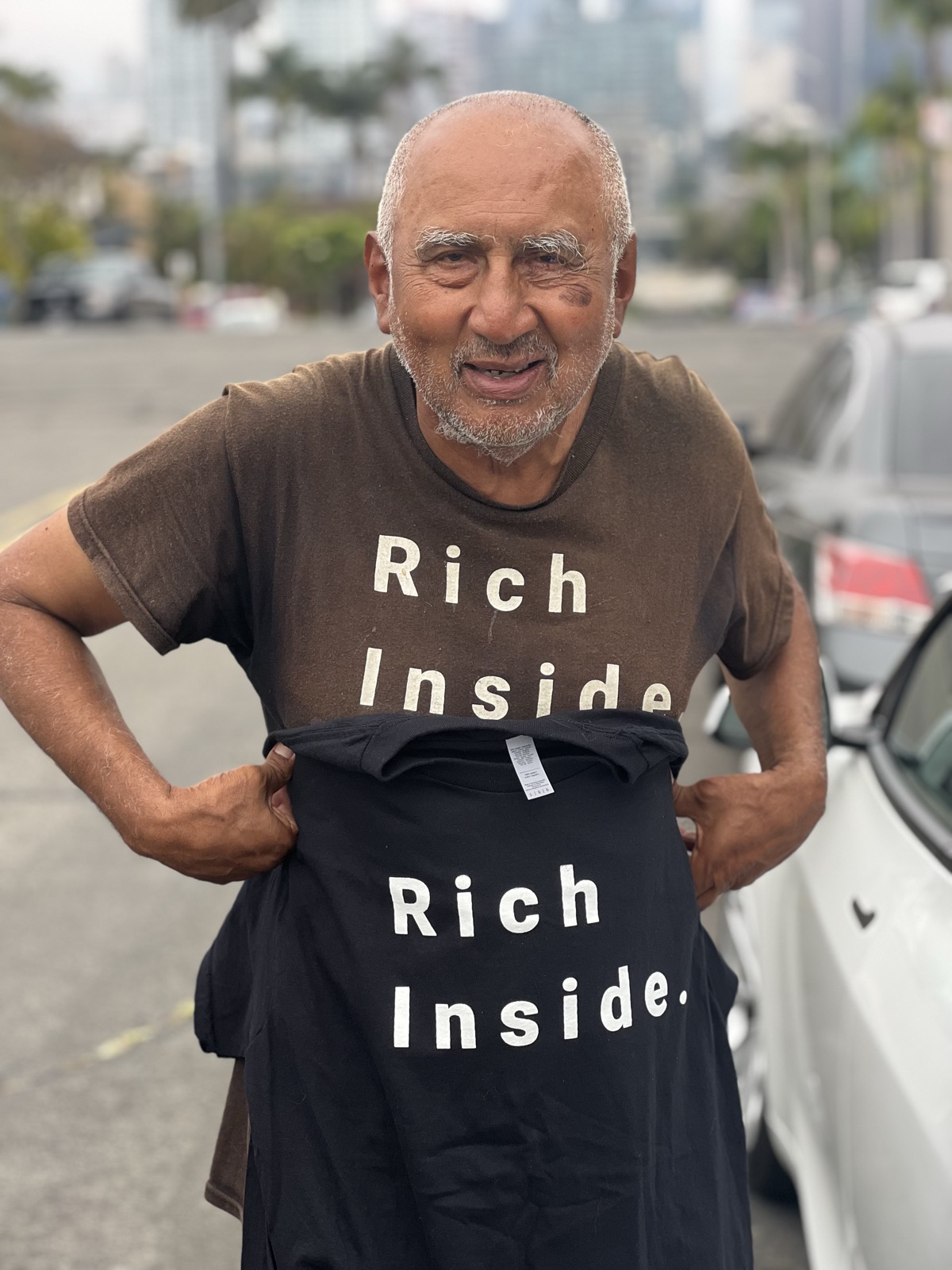 Man holding up a Rich Inside tee